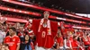 Ein treuer Benfica-Fan in einem auffälligen roten Bischofskostüm feiert inmitten der jubelnden Menge auf der Tribüne des Stadions.